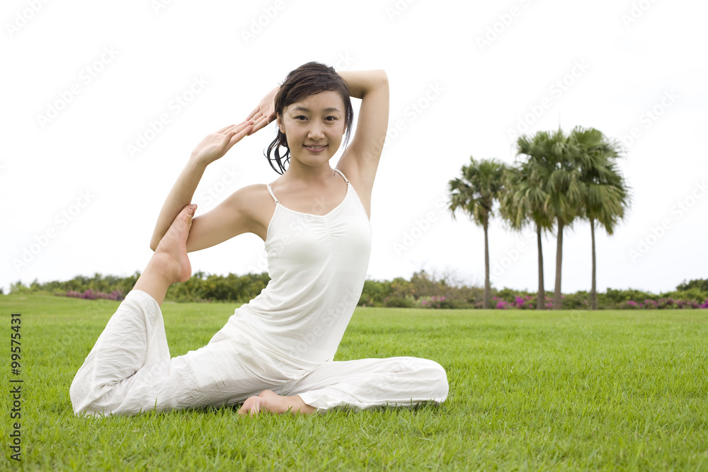 A woman practicing yoga on a grass field