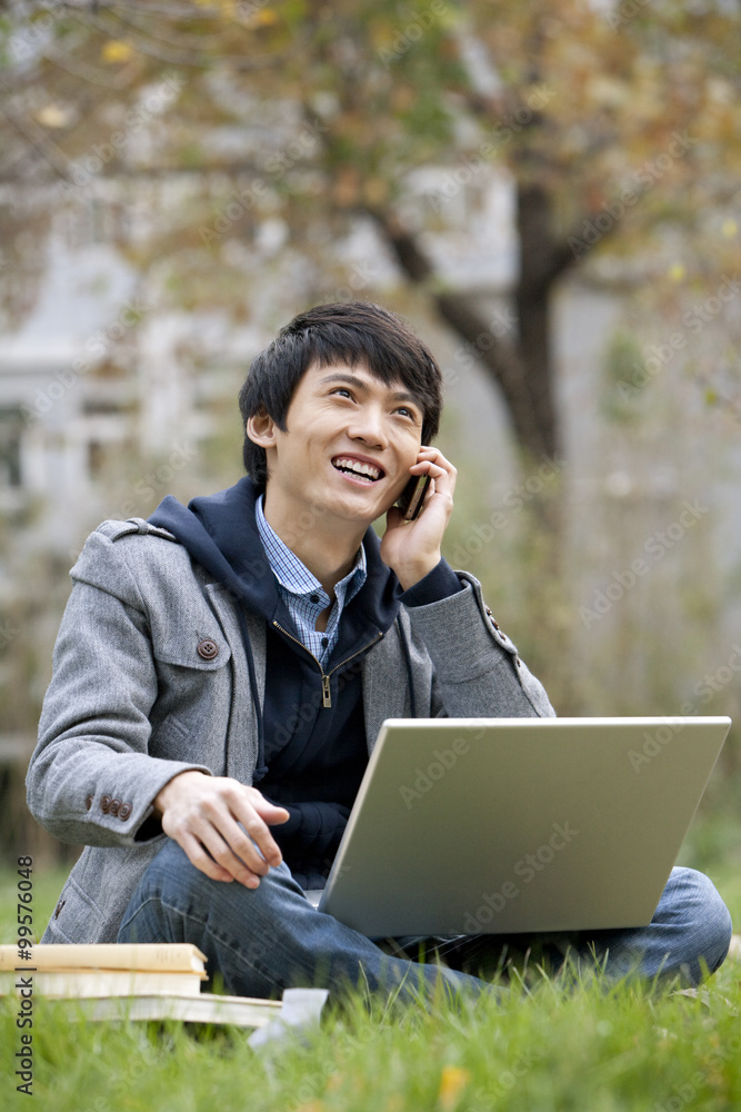 A young man talking on the phone and using computer