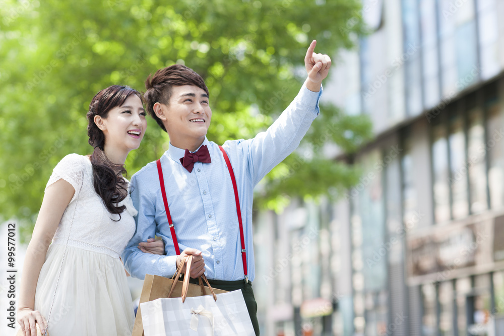 Stylish young couple walking with shopping bags in hand