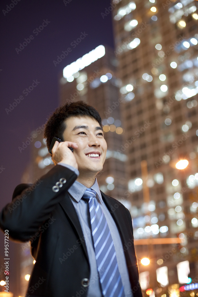 Chinese businessman using cellphone with city lights in the background