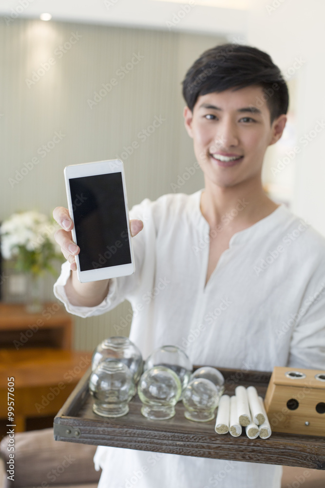 Traditional Chinese medical massagist showing a smart phone