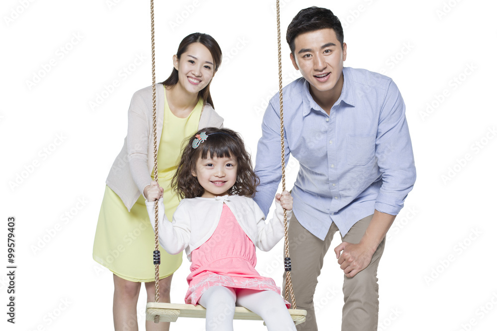 Young parents pushing daughter on swing