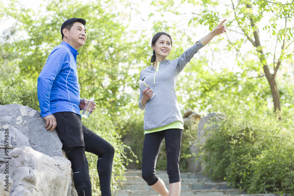 Happy mature couple holding bottled water after exercising