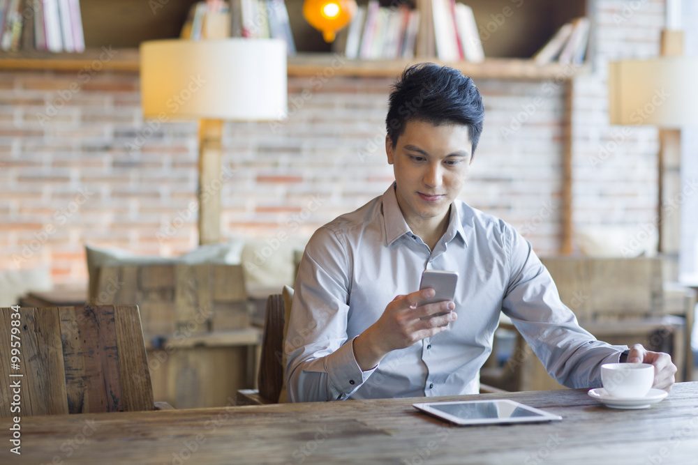 Young man using smart phone in cafe