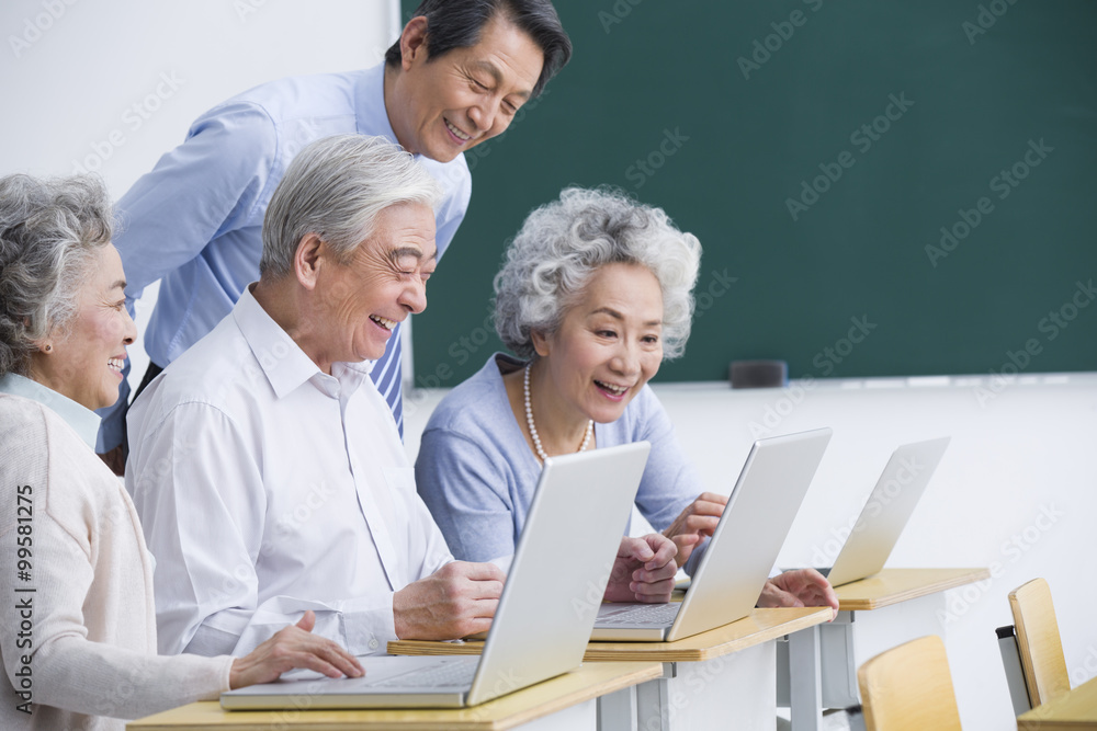 Senior adults having computer class at school