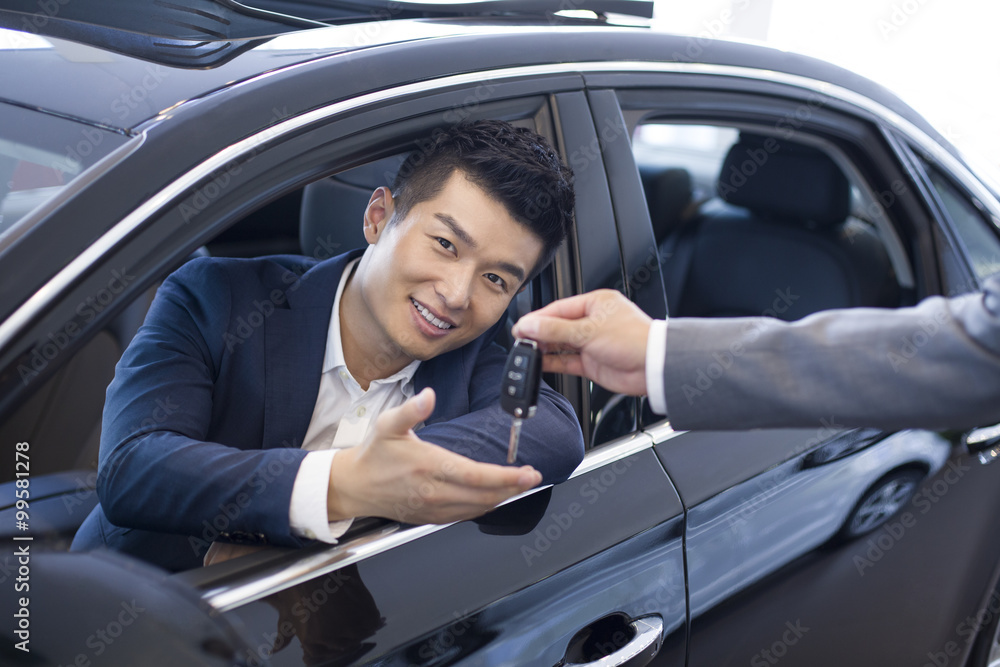 Young businessman buying car in showroom