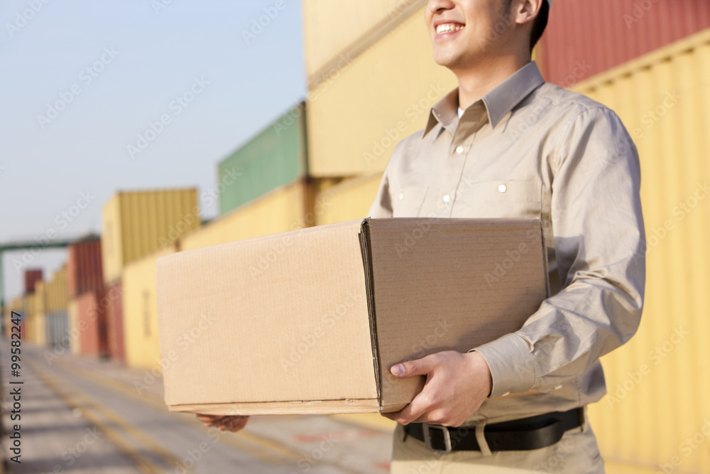 Shipping industry worker carrying a cardboard box