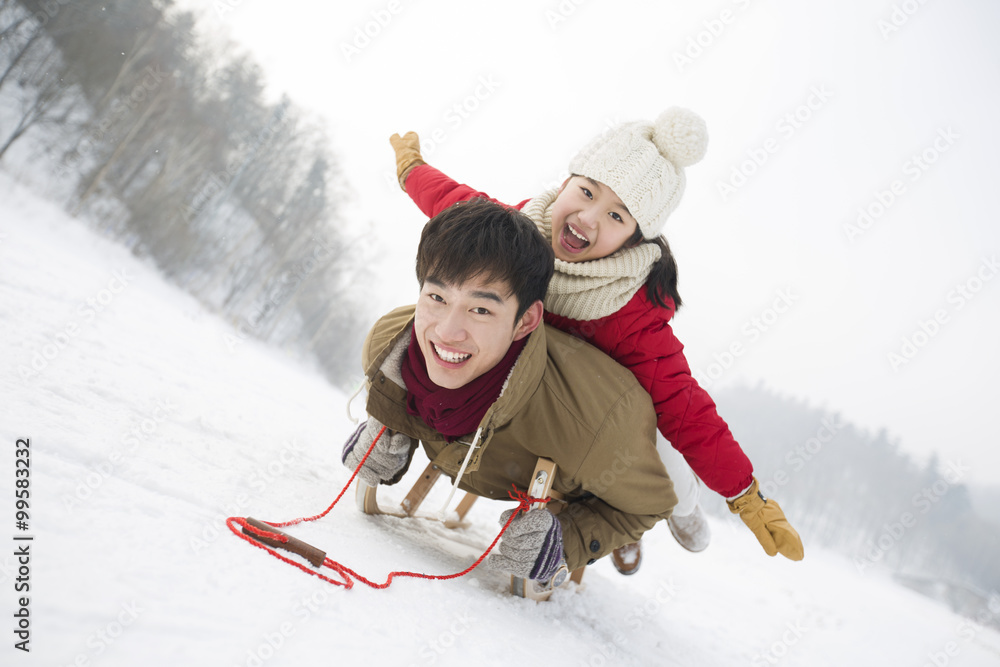 年轻的父女在雪橇上滑行