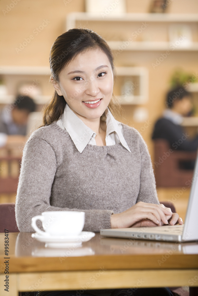 年轻女子在咖啡店使用笔记本电脑