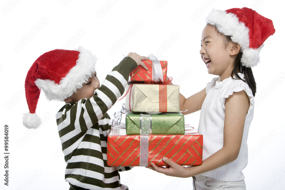 Boy and girl with Santa hats holding gift box