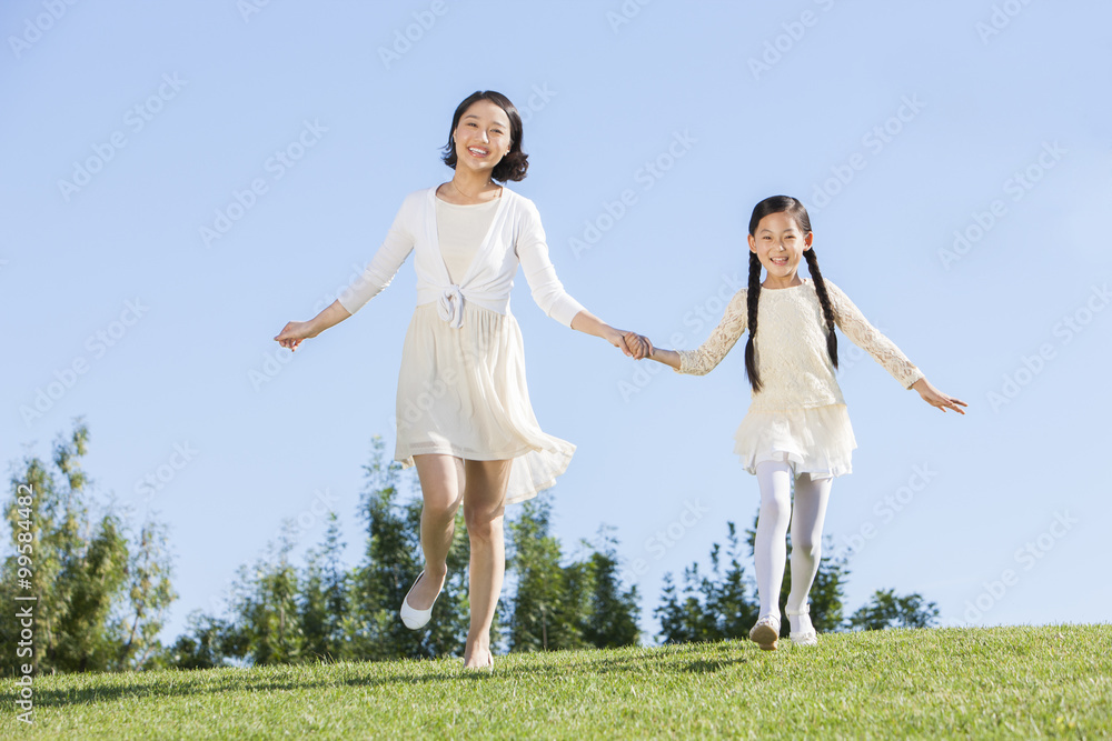 Happy mother and daughter holding hands on the lawn