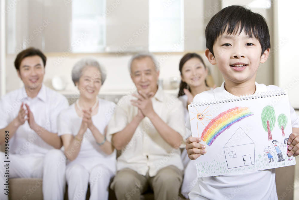 小男孩在家人面前举起一幅画