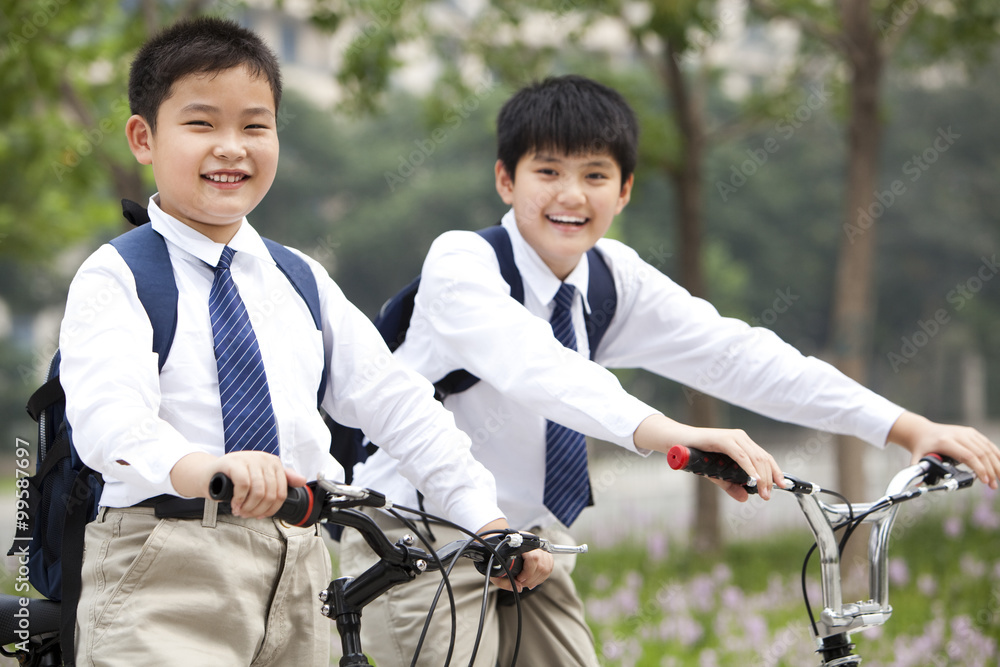 快乐的穿着制服的男生在户外骑自行车