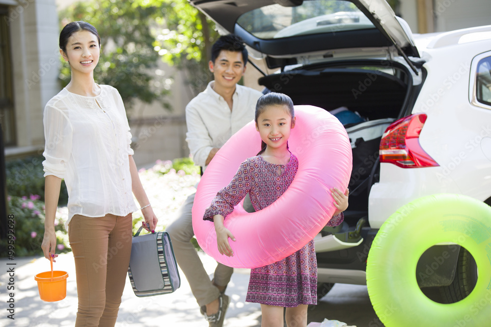 Young family putting water sports equipment into the car