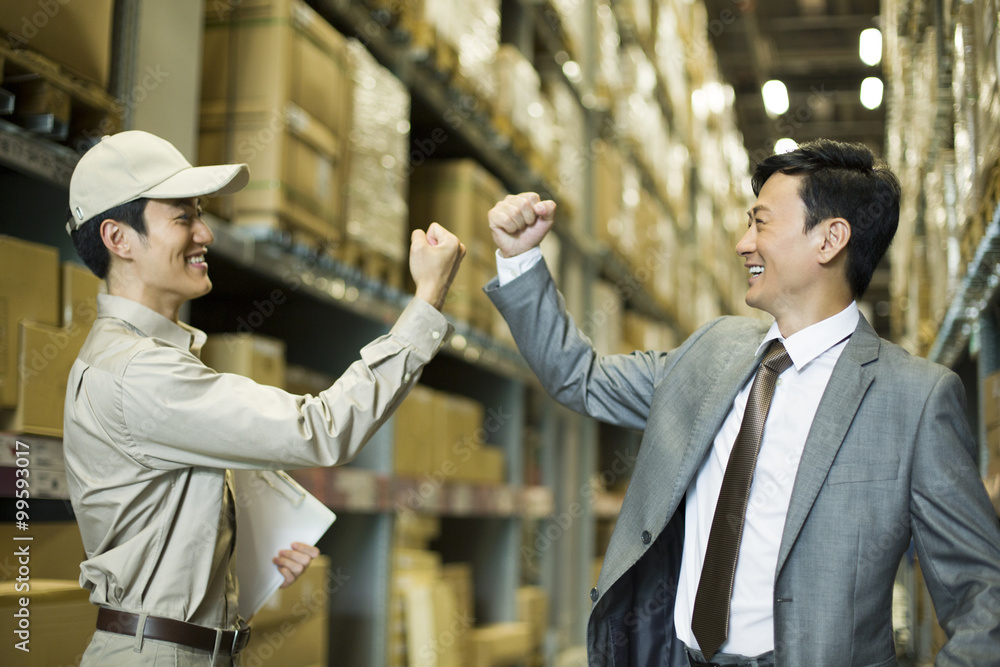 Young logistics staff punching the air with businessman