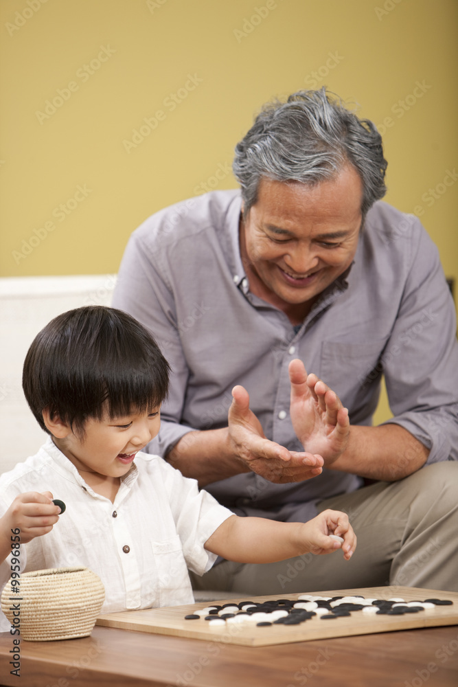 Little boy playing Chinese game of Go with grandfather