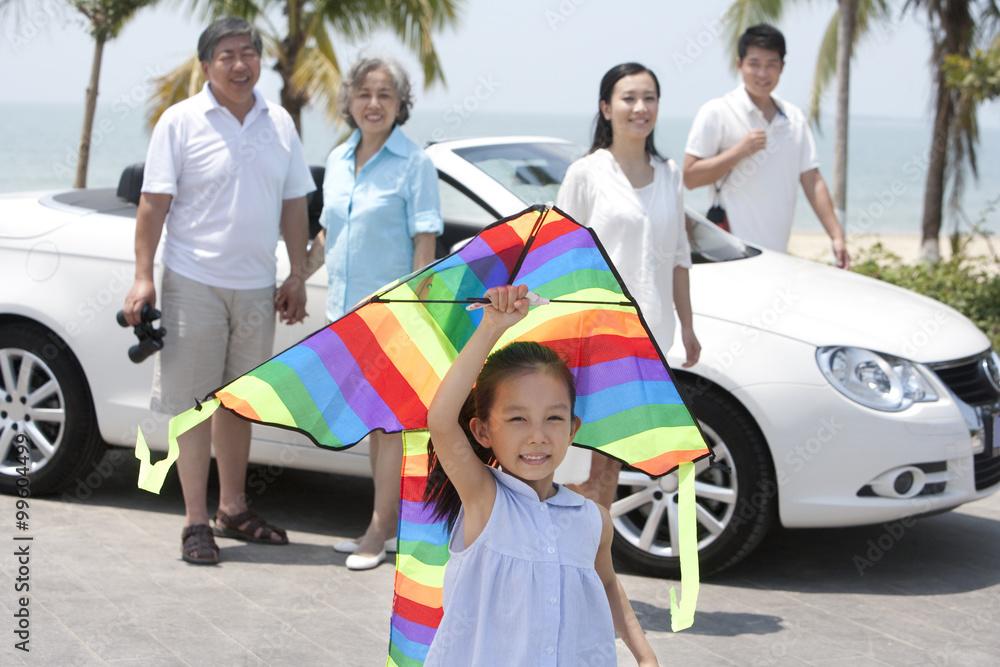 Girl Flying Kite with Family in Background