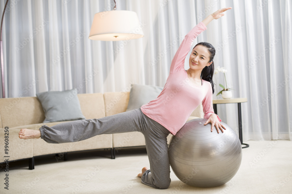 Young woman practicing yoga with fitness ball