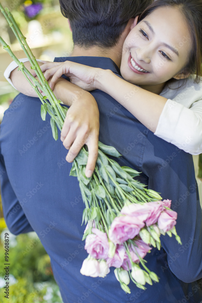 年轻女子用鲜花拥抱男友