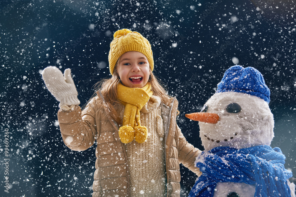 girl plaing with a snowman