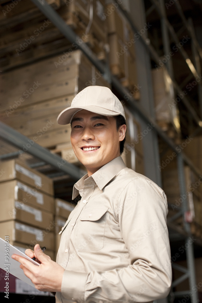 Male Chinese warehouse worker with clipboard