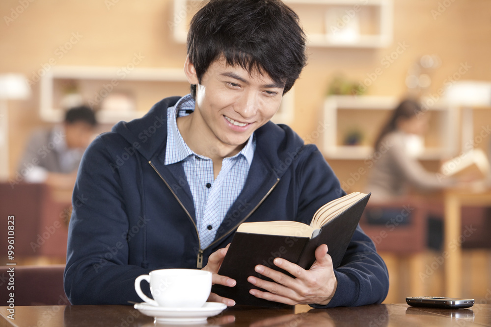 Young man reading a book at a coffee shop