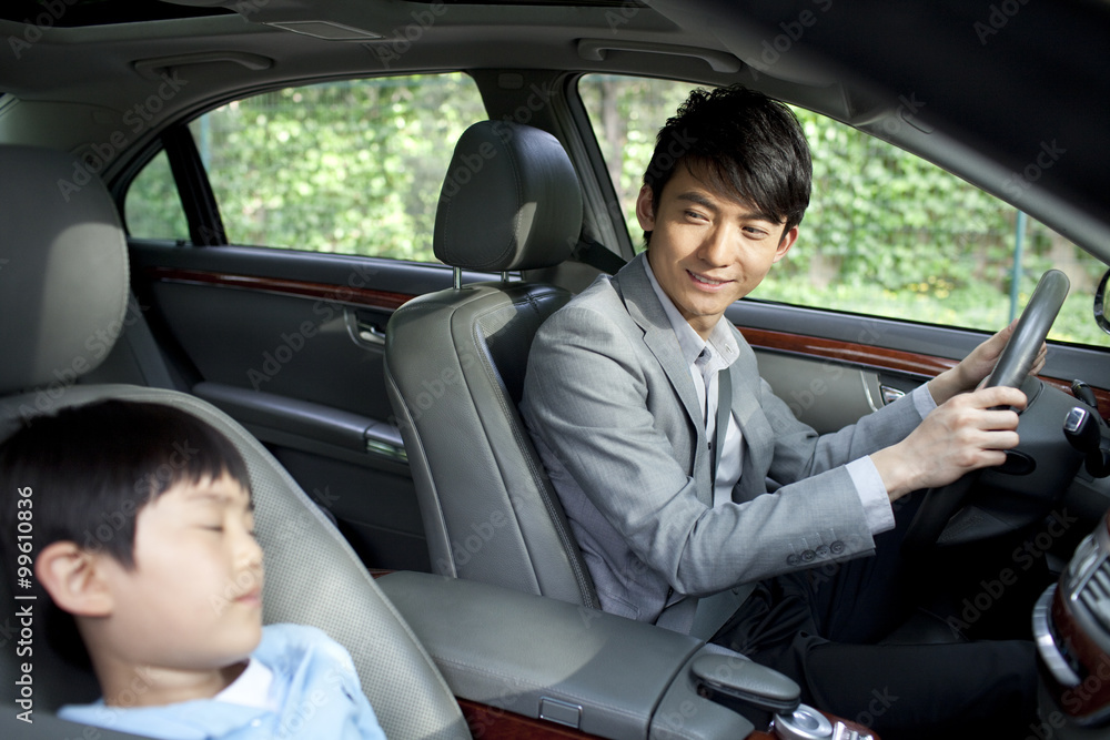 Cheerful father driving with son sleeping in front seat