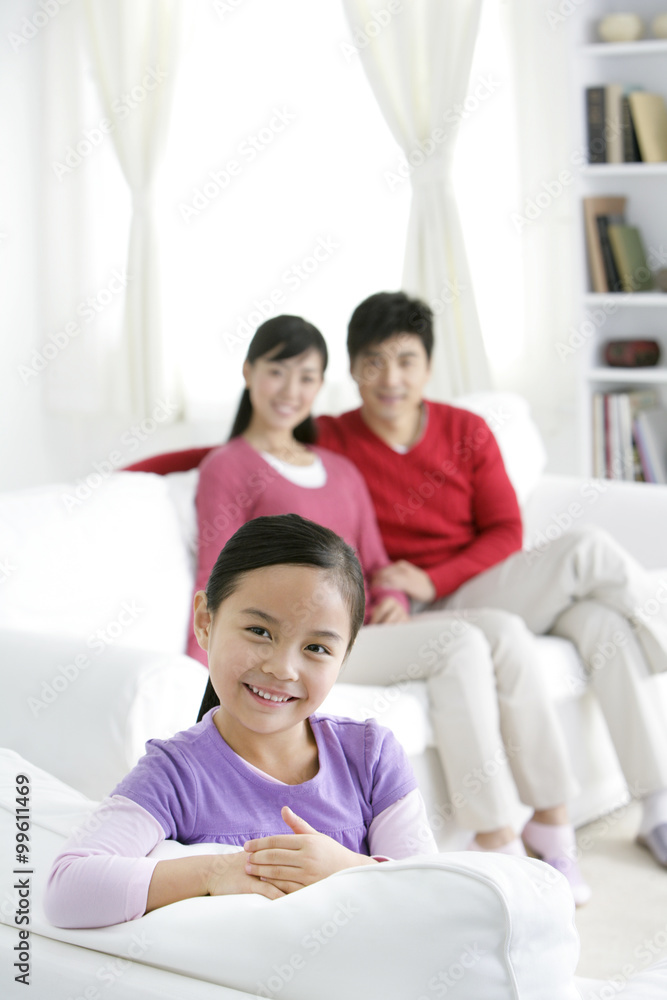 Young Chinese girl in a living room with parents in the background