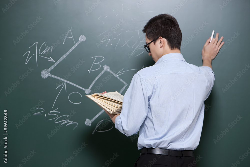 Professional male teacher writing on blackboard