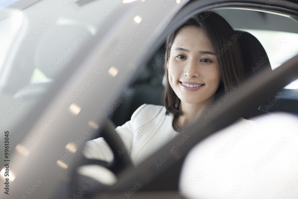 Young woman choosing car in showroom