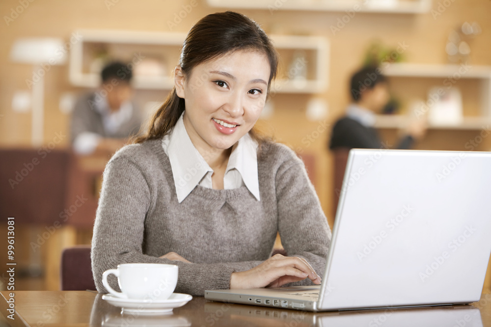 young woman using laptop in coffee shop