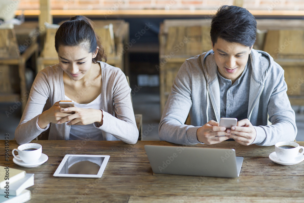 Young couple using smart phone in cafe