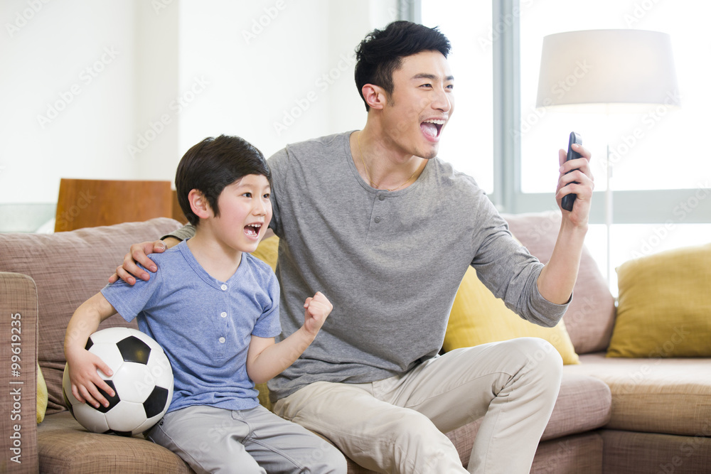 Excited father and son watching football on TV