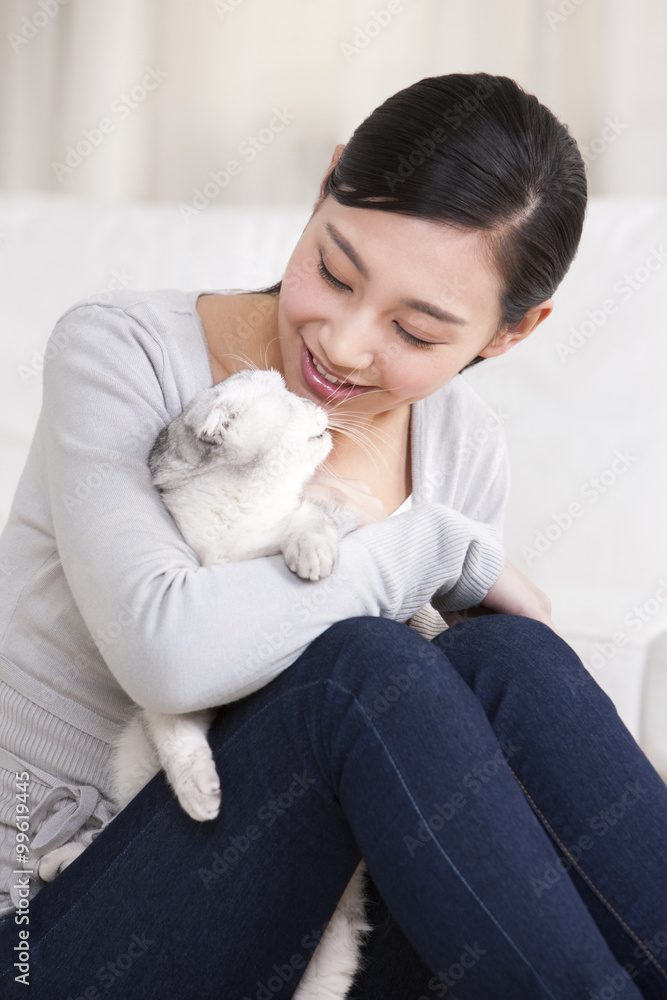 年轻女子与苏格兰折叠猫玩耍