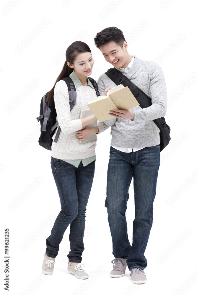 Happy college couple studying a book