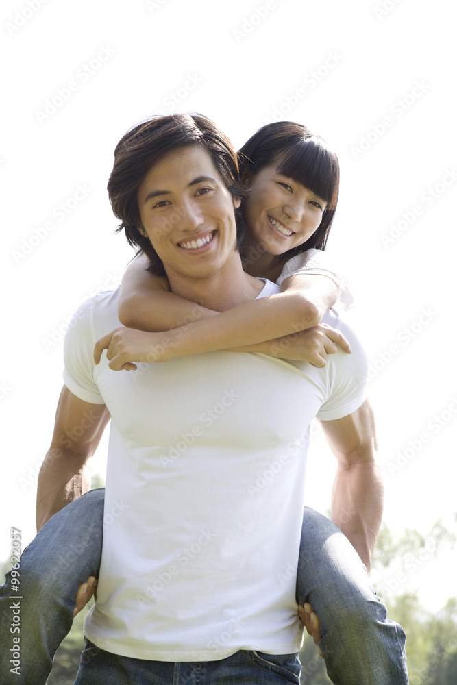 Young man carrying young woman on back