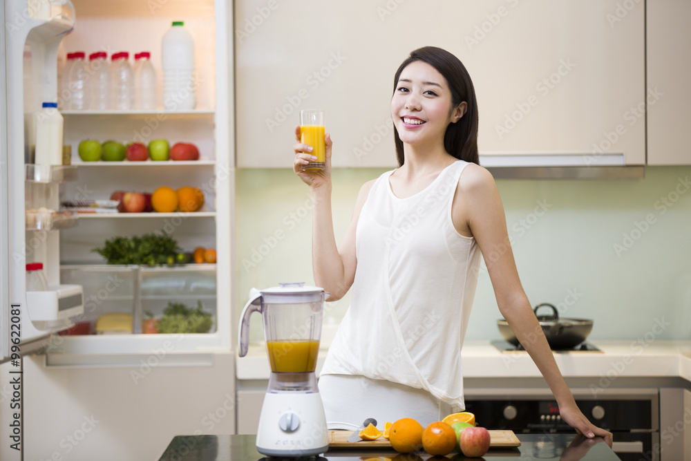 厨房里拿着一杯新鲜果汁的年轻女子