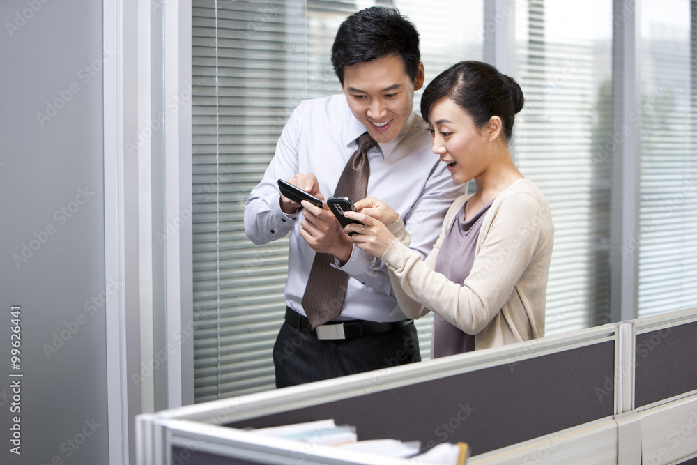 Young Businessman and Businesswoman Comparing Pictures