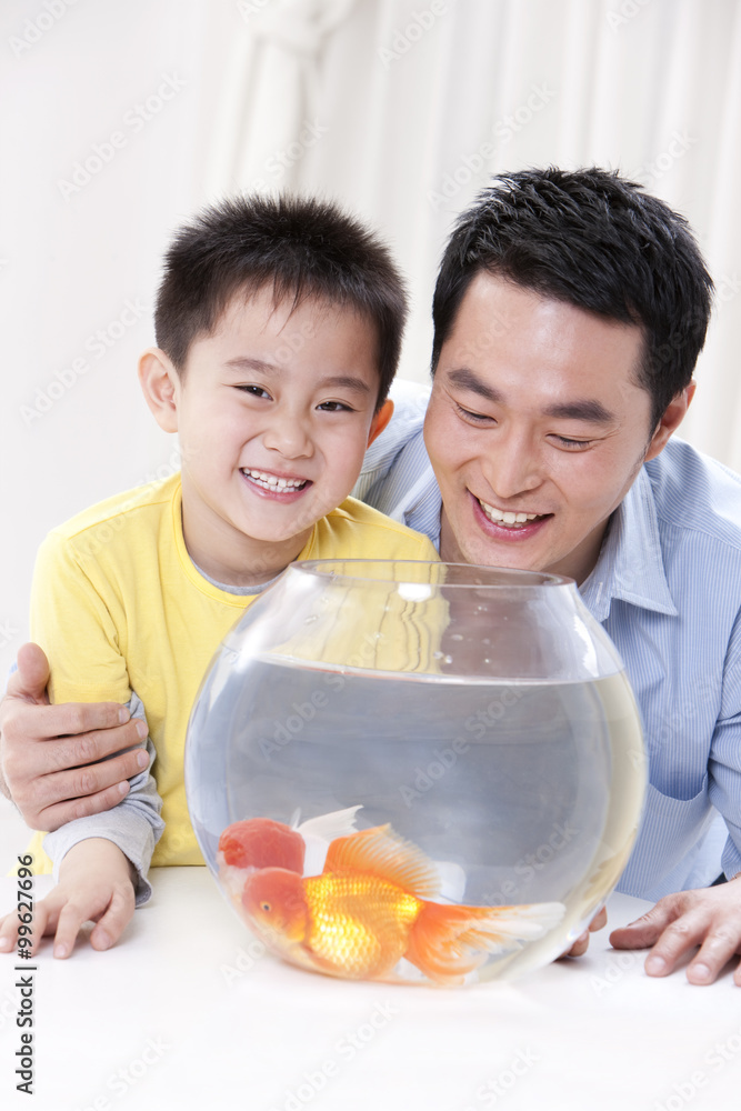 Father and son having fun with goldfishes