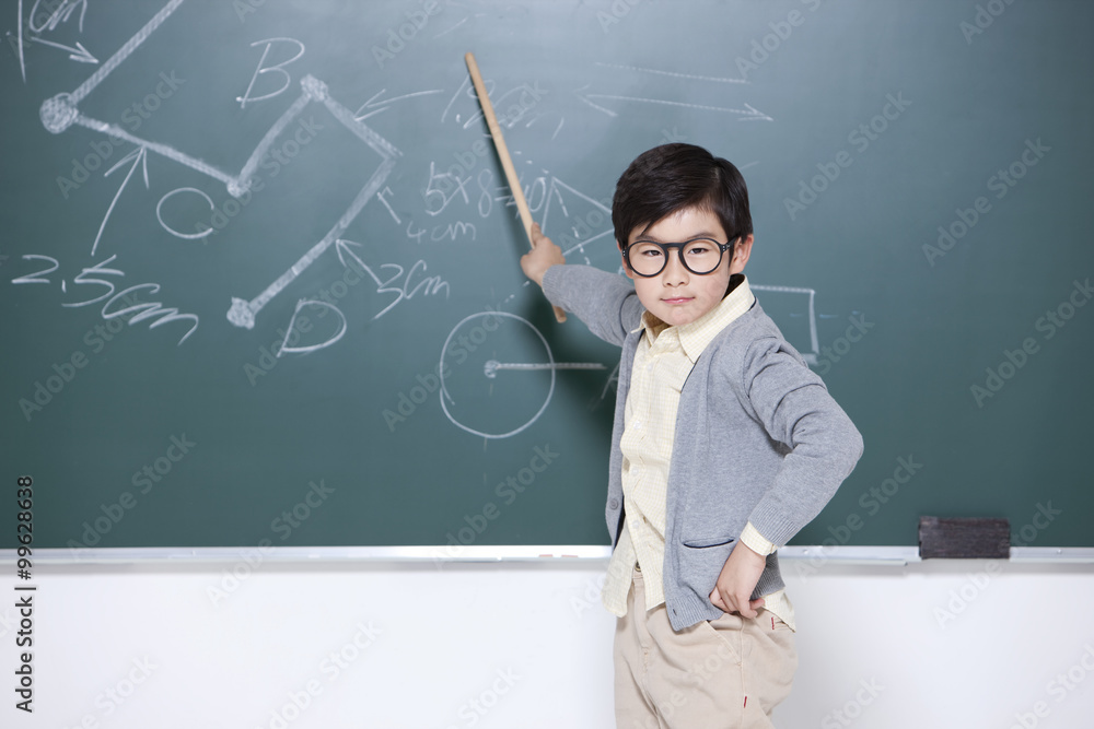 Active little boy playing teacher in classroom