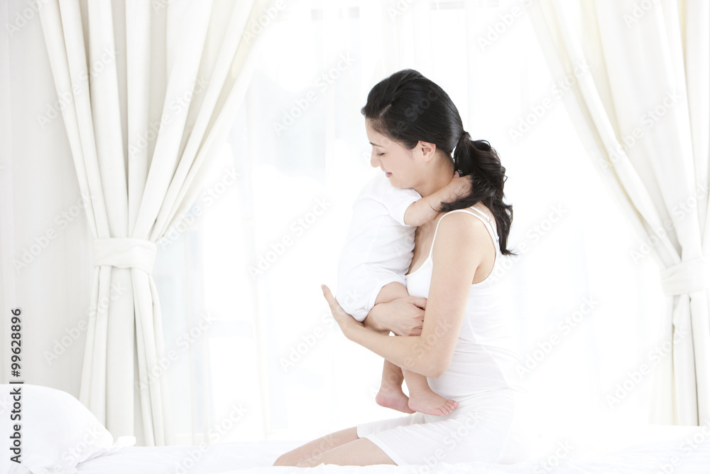 Gentle mother and cute baby in bedroom