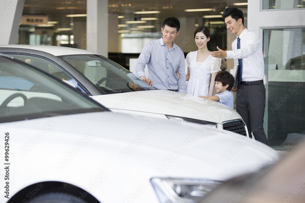 Young family choosing car in showroom