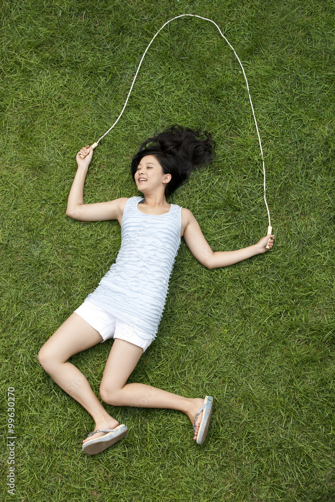 Creative young woman imitating jumping rope on meadow