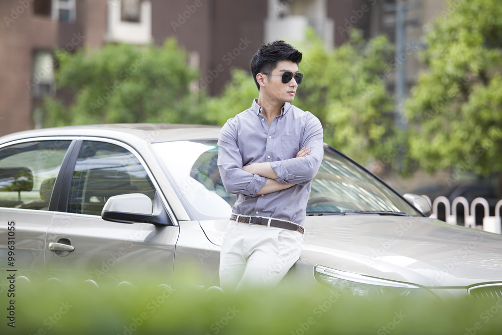 Young man leaning against his car