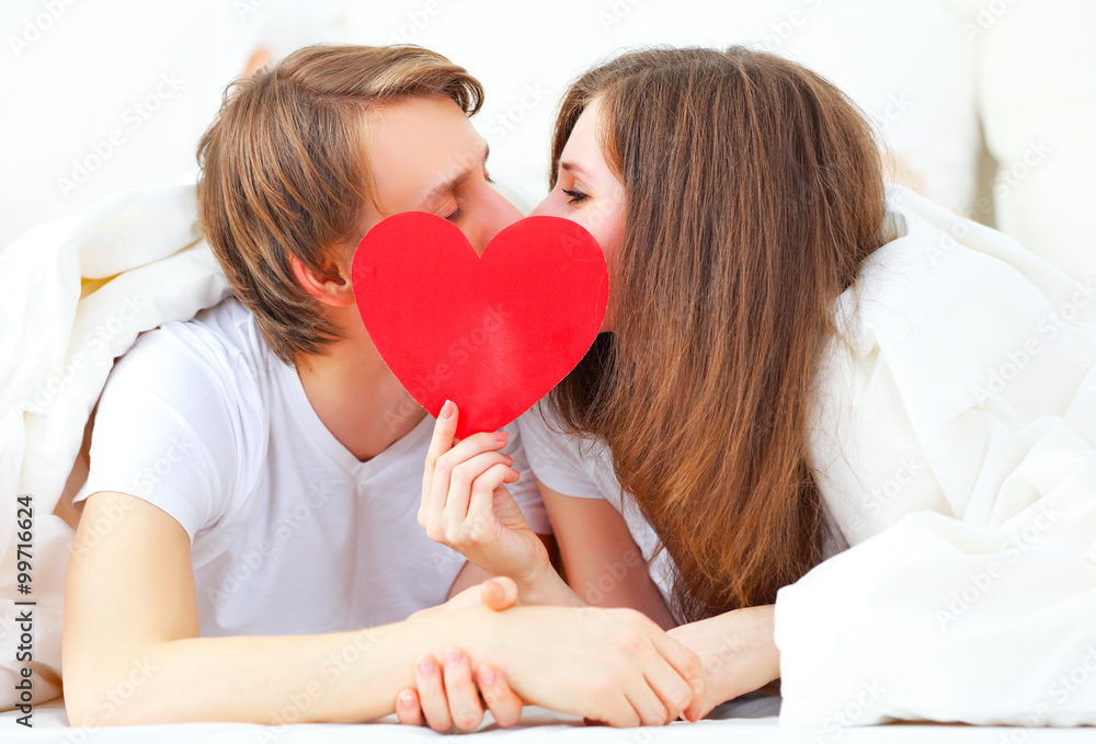 lover couple kissing with a red heart in bed