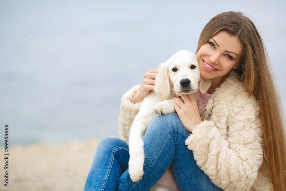 海边一名年轻女子带着一只小狗寻回犬