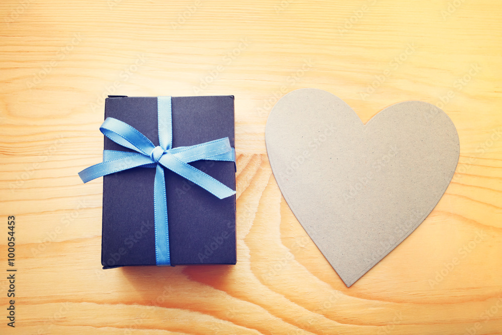 Giftbox and hand cut heart on wooden table