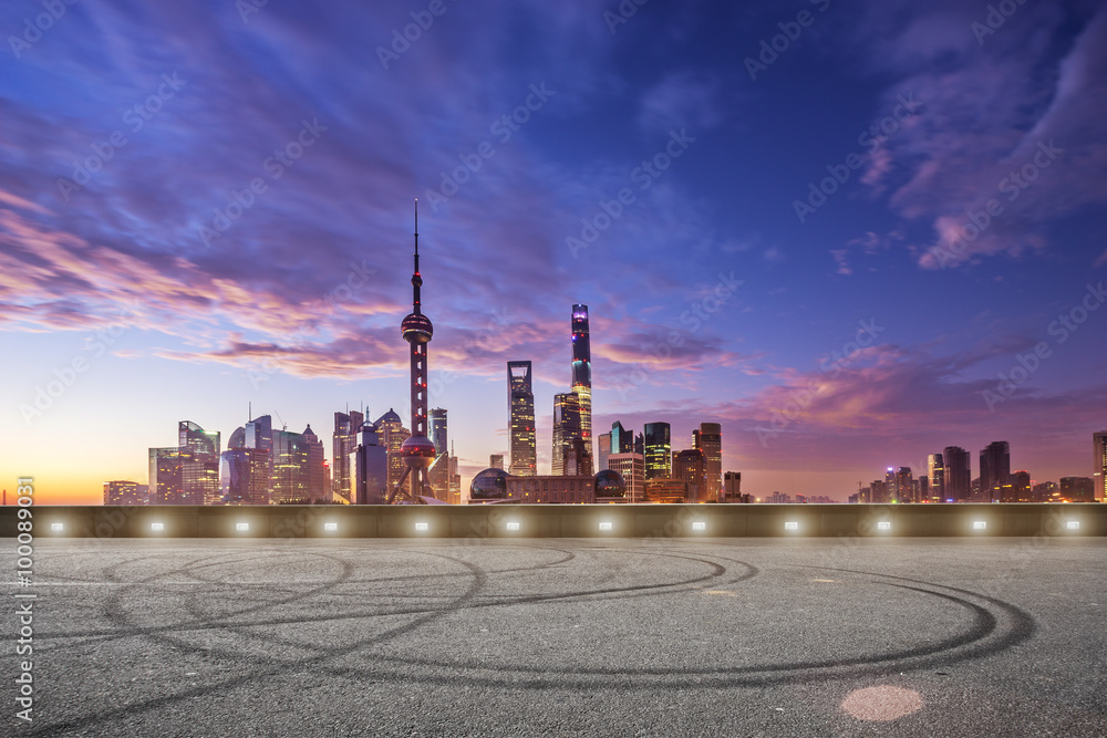 empty asphalt road and cityscape in colorful sky at dawn