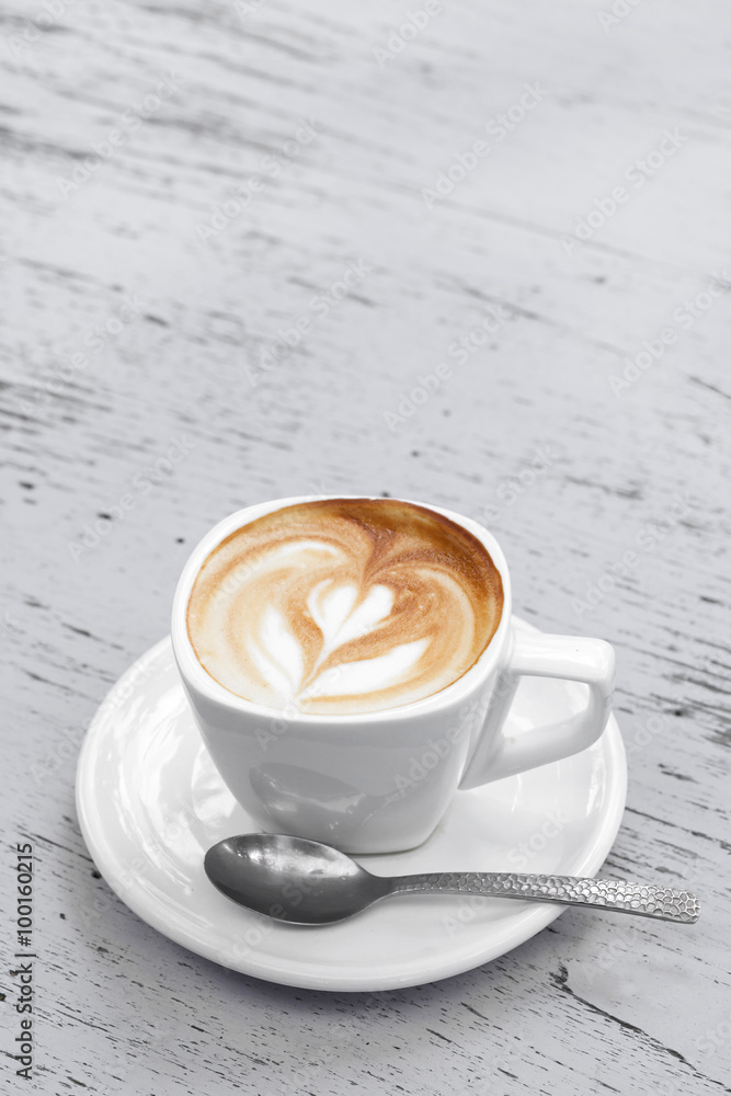 A Cup of latte coffee on white wood table