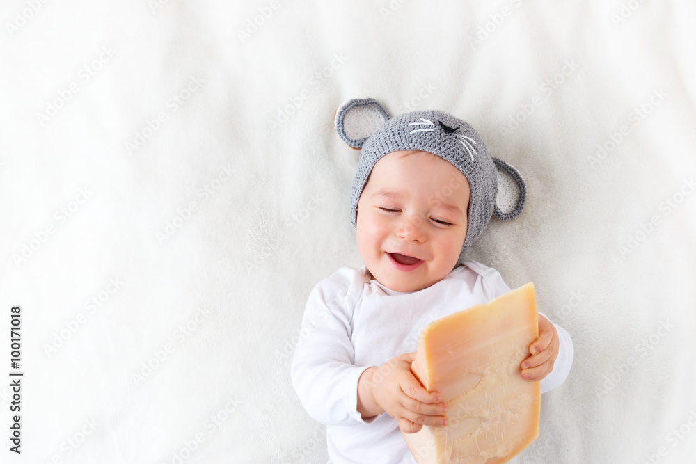 Baby boy in mouse hat lying on blanket with cheese